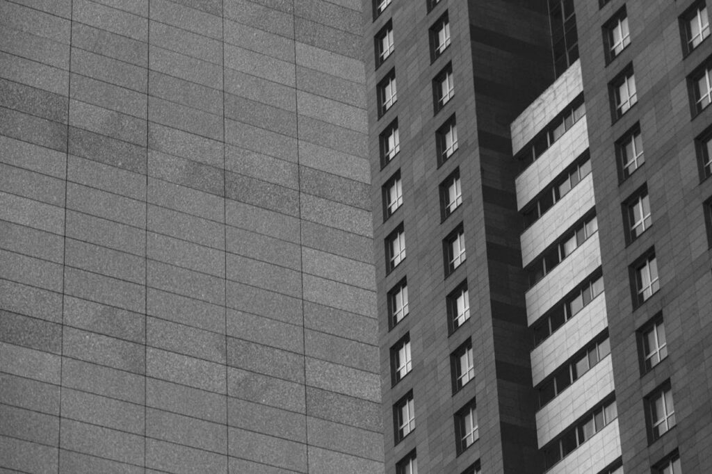 Mastering the First Impression: Your intriguing post title goes here A monochrome photo capturing the sleek architecture of modern high-rise buildings with grid-like patterns.