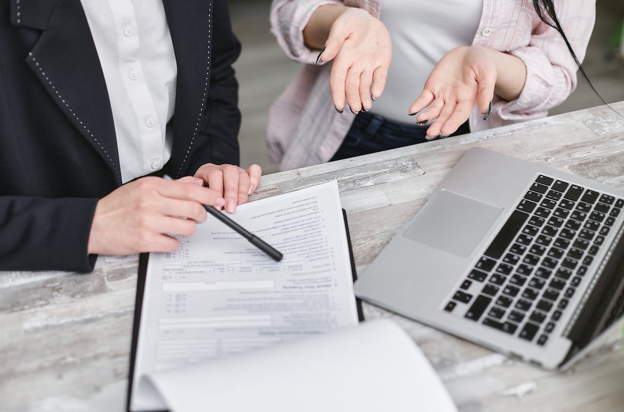 The Art of Drawing Readers In: Your attractive post title goes here Two professionals discussing a contract at a business meeting with documents and a laptop.